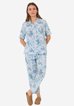 Lichtblauw pyjama set met korte mouwen en bloemenpatroon in tinten van blauw en wit. Zachte stof, bijpassende broek en bruine instap schoenen.