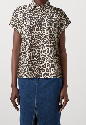 Blusa a maniche corte con stampa leopardata realizzata in tessuto morbido, dotata di colletto e bottoni sul davanti, abbinata a una gonna di jeans.