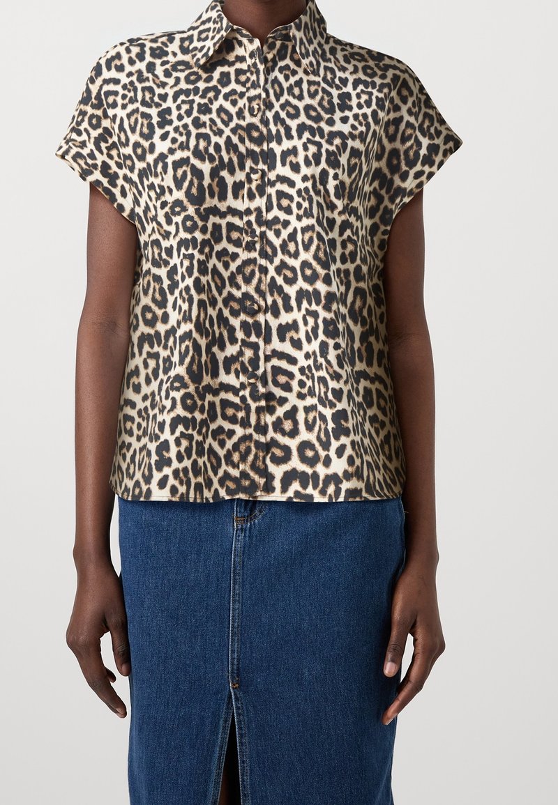 Leopardenmuster, kurzärmlige Bluse aus glattem Stoff, mit Kragen und Knöpfen auf der Vorderseite, kombiniert mit einem Jeansrock.