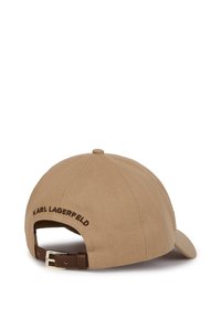 Beige baseball cap made of textured fabric. Features a brown leather strap and gold hardware, with "KARL LAGERFELD" embroidered at the back.
