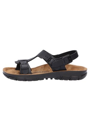 Black sandals with adjustable straps, cork footbed, textured rubber outsole, open design, and minimal hardware detailing.
