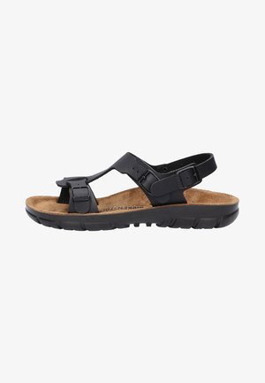 Schwarze Sandalen mit verstellbaren Riemen, Korkfußbett, strukturiertem Gummifußboden, offenem Design und minimaler Hardware-Detaillierung.