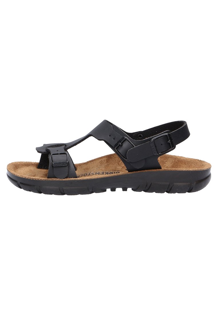 Schwarze Sandalen mit verstellbaren Riemen, Korkfußbett, strukturiertem Gummifußboden, offenem Design und minimaler Hardware-Detaillierung.