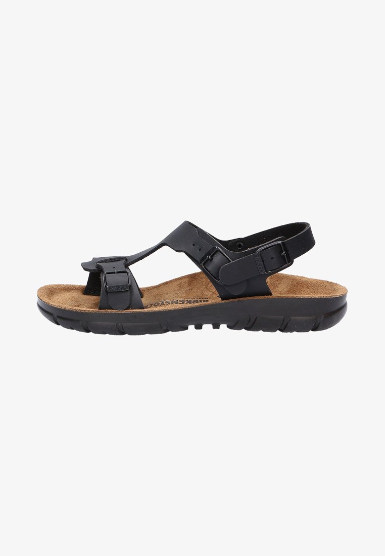 Schwarze Sandalen mit verstellbaren Riemen, Korkfußbett, strukturiertem Gummifußboden, offenem Design und minimaler Hardware-Detaillierung.