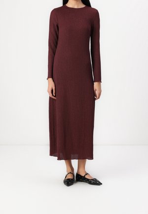 Bordowa sukienka z długim rękawem, o prążkowanej teksturze, z prostym krojem i okrągłym dekoltem, zestawiona z czarnymi czółenkami w szpic z oczkowymi detalami.