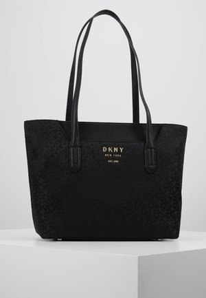 Bolso tote negro de DKNY con dos asas para el hombro, textura sutil con patrón y texto del logo dorado en el frontal.