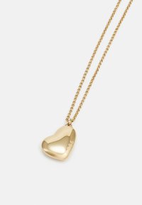 Collana con pendente a forma di cuore in oro su una catena, caratterizzata da una texture lucidata e un logo inciso, con un design snello e maglie.
