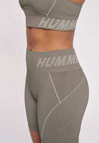 Olivgrön sportbh och högmidjade shorts med ribbat mönster, kontrasterande logoband och chevrondetaljer på shortsen.