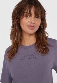 Lilla kortærmet t-shirt lavet af blødt stof, med et lille, stiliseret 'O'Neill' logo trykt på brystet i en mørkere nuance.