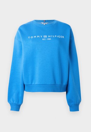 Hanorac albastru, cu mâneci lungi, cu manșete și tiv ondulat. Prezintă logo-ul alb "TOMMY HILFIGER EST. 1985" pe partea din față. Textură netedă.