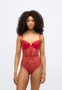 Κόκκινο διαφανές κορμάκι με επενδυμένους κυπέλλους, διακοσμητικά σχέδια καρδιών και λεπτές τιράντες. Διαθέτει εφαρμοστή σιλουέτα και διακοσμητικές λεπτομέρειες από δαντέλα.