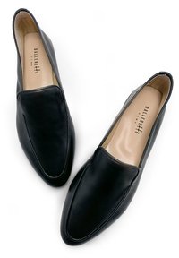Black leather slip-on shoes featuring a smooth surface, rounded toe, and a minimalistic design with a soft inner lining.