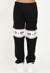 Svarta sweatpants med vitt och rosa ögondiagramdetalj vid underbenet, med ett bekvämt elastiskt midjeband och mjukt tyg.