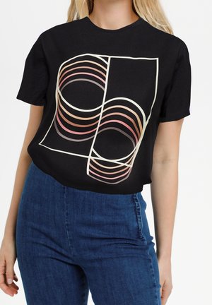 Sort kortærmet t-shirt med et geometrisk design af overlappende buede linjer i nuancer af pink og fersken på fronten.