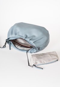 Helles blaues Lederhandtasche mit gerafftem Oberteil und Reißverschluss, ausgestattet mit einem gemusterten Innenfutter und einer kleinen passenden Tasche.