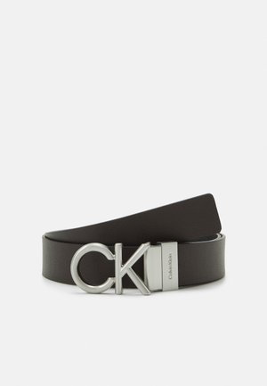 Sort læderbælte rullet sammen med sølv metalspænde med store CK-initialer og Calvin Klein indgraveret på låsen.