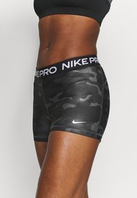 Fitted szorty w czarnym wzorze kamuflażu z szerokim elastycznym pasem, z białym brandingiem "NIKE PRO" oraz małym białym logo Nike.