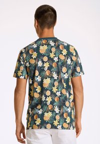 Camisa de manga corta con un fondo verde oscuro y un vibrante patrón de flores y frutas cítricas, fabricada con tejido ligero.