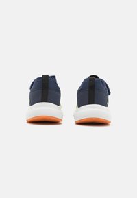 Marine textielschoenen met een witte zool en een oranje rubberen buitenzool. Bevat een zwarte hieltab en groene accenten aan de zijkanten.