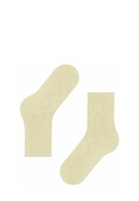 Para jasnobrązowych skarpetek do kostek z delikatnym, kropkowanym wzorem zygzaka, jedna skarpetka leży płasko, druga jest ustawiona pod kątem, aby pokazać podeszwę.