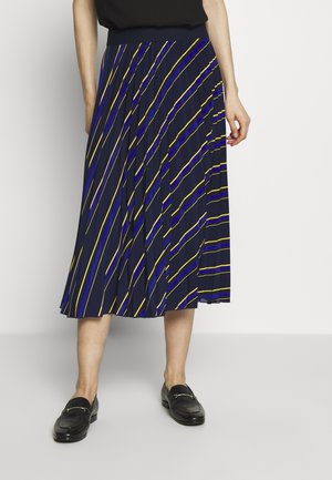 Modrá plisovaná sukně se žlutými a modrými šikmými pruhy, z lehké látky, s elastickým pasem, v kombinaci s černými mokasínami.