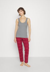 Grå singlet og røde rutete pysjamasbukser med rosa detaljer. Singlet har scoop hals, mens buksene har slim fit.