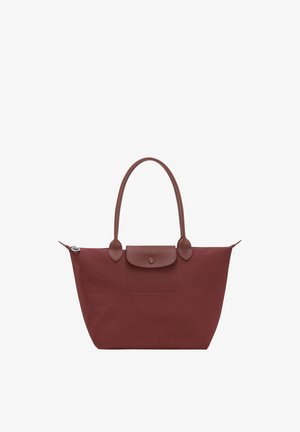 Brown tote bag with long handles, a front buttoned flap pocket, and a zippered main compartment.