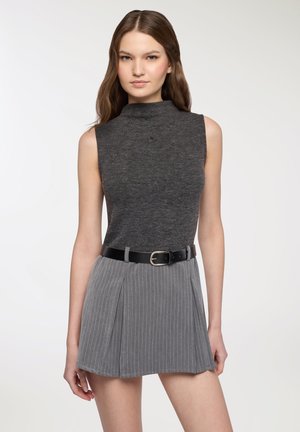 Top a collo alto senza maniche grigio abbinato a una gonna grigia a righe sottili, con cintura nera con fibbia argentata, tessuto liscio e silhouette aderente.