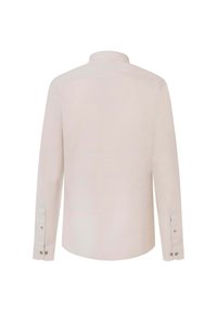 Camisa de manga larga color beige claro con cuello de botón. Presenta una textura suave y botones en los puños. Se muestra vista trasera.