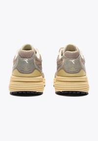 Pair of beige and brown athletic shoes shown from the back with thick, textured yellow soles and mesh and suede upper material.