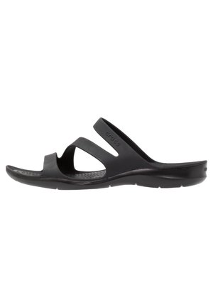 Sandale noire en plastique flexible, avec une semelle intérieure texturée, des doubles brides croisées et une épaisse semelle rembourrée.
