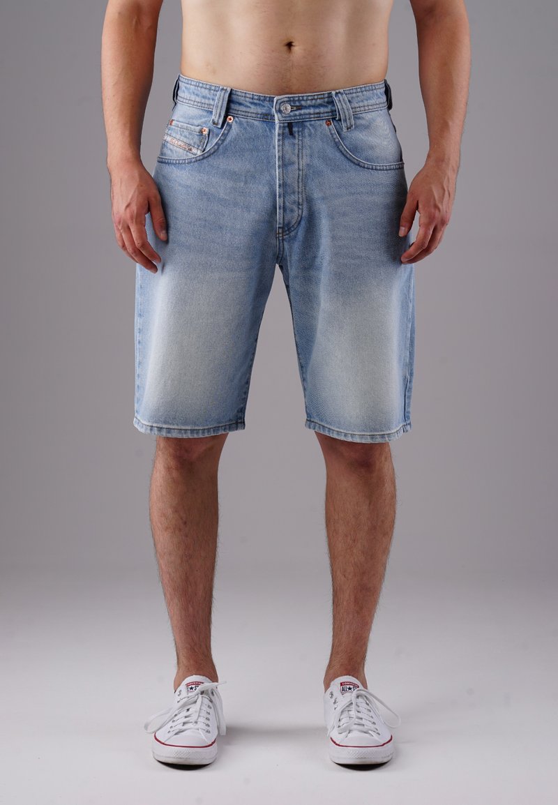 Light blue denim shorts with a faded pattern, five pockets, and a straight leg design, worn with white sneakers.