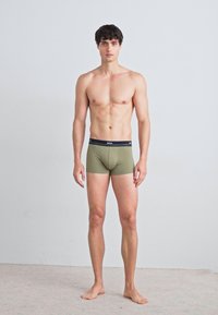 Olivgrüne Boxershorts mit einem schwarzen Bündchen, das den Markennamen trägt. Der Stoff wirkt glatt und enganliegend und zeigt ein schlichtes Design.