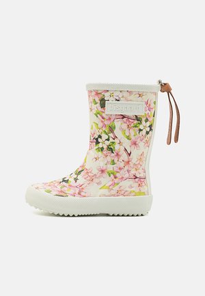 Barns hvid gummistøvle med lyserødt og grønt blomstermønster, hvid sål og brun læderstrop bagpå.