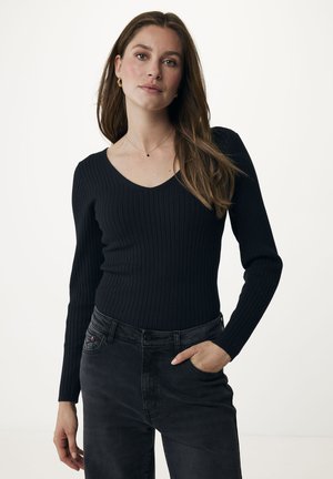 Sort ribbet langærmet top med dyb V-hals, parret med mørkegrå bukser. Toppen har en tætsiddende silhuet og tekstureret stof.