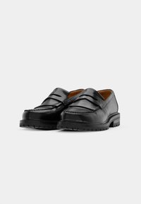 Black leather loafers with a smooth finish, featuring two decorative straps, a stitched border, and a textured rubber sole.