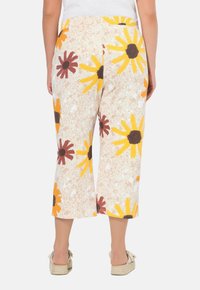 Bloemige cropped broeken in crème met gele en bruine bloemen, gestructureerde stof, elastische tailleband en een relaxte pasvorm.