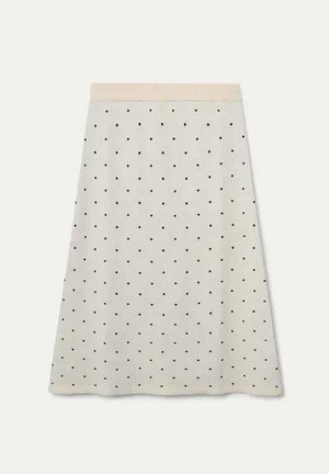 Una falda de crema hasta la rodilla con una cinturilla ajustada, que presenta un patrón de pequeños lunares negros y una textura de tela suave.