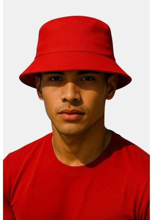 Rode stoffenhoed met een brede rand. Draagt door een persoon in een bijpassend rood T-shirt tegen een effen achtergrond.