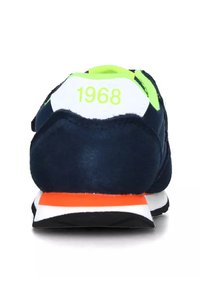 Sneakers in suede blu navy con tallone bianco e verde neon, caratterizzati da un accento arancione sulla suola e l'anno "1968" stampato in verde.