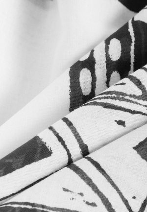 Melnbaltā auduma ar rakstiem, kurā ir izteikti līnijas un apļveida formas, ar maigu, teksturētu apdari. Kliegumi rada dziļumu un ēnas.