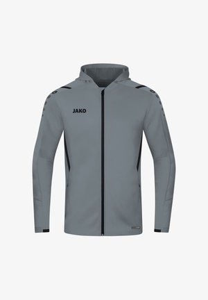 Graue Kapuzenjacke mit Reißverschluss, schwarze Akzente, JAKO-Logo auf der Brust und kleine Punkte entlang von Schulter und Oberarm.