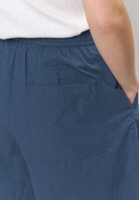 Laivastonsiniset kevyet shortsit, joissa on joustava vyötärönauha ja yksi takatasku, sileä pinta ja rento istuvuus.