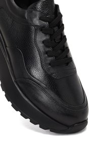 Sneaker in pelle nera con finitura testurizzata, accenti opachi e lucidi a contrasto, punta rotonda e suola in gomma spessa con motivo sul battistrada.