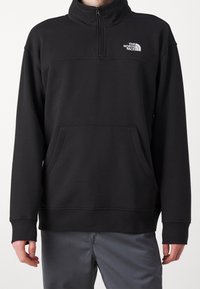 Pullover in felpa nera con collo alto, mezza zip e tasca frontale. Presenta un logo bianco sul lato sinistro del petto e polsini a coste.