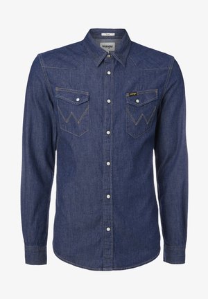 Camisa de mezclilla azul oscuro de manga larga con cuello puntiagudo, dos bolsillos en el pecho, costuras en amarillo contrastante y cierre frontal de botones.