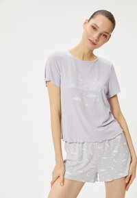 Lyse lilla bomulds-pyjamas sæt med en kortærmet top med måne- og stjernemotiv, suppleret med mønstrede shorts med en blød tekstur.