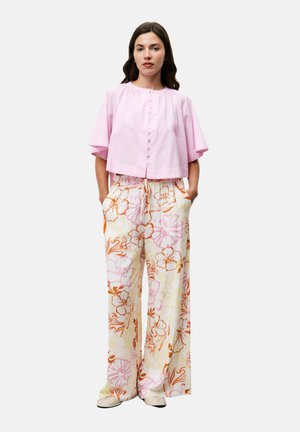 Pink cropped button-up top with short sleeves, paired with wide-leg floral pants in pastel colors and beige slip-on shoes.