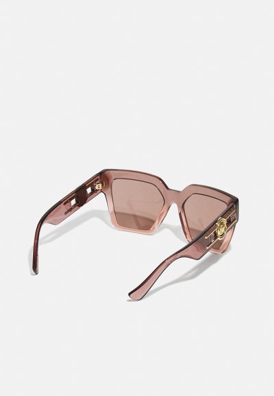 Ochelari de soare cu o formă hexagonală, rame transparente roz, lentile maro și accente de hardware aurie pe brate.