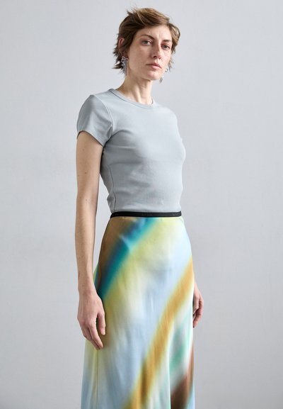 Light gray ribbed short-sleeve top paired with a flowing, multicolored maxi skirt featuring blue, green, and brown abstract patterns.